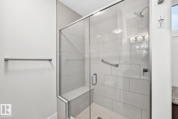 Glass-enclosed shower with a built-in bench, subway tile surround, rainfall shower head, and a chrome grab bar - 