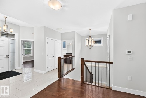 Foyer featuring tile flooring, a staircase with wood-finish handrail and metal spindles, and a multi-panel entry door with transom window - #57 18343 Lessard Rd Nw, Edmonton, AB - Indoor Photo Showing Other Room