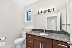 Vanity with a granite countertop, undermount sink, and wood-finish cabinetry - 