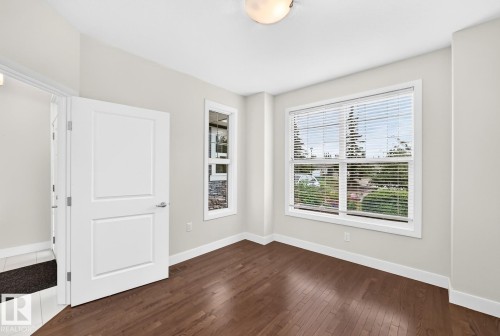 Hardwood-finish flooring, white trim, recessed lighting, and a large window with blinds - #57 18343 Lessard Rd Nw, Edmonton, AB - Indoor Photo Showing Other Room