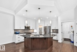 Kitchen featuring wood-finish flooring, white cabinetry, dark countertops, and stainless steel appliances - 
