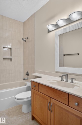Tile flooring, light wood-finish vanity, integrated sink, tile shower surround with recessed niche, and a combination tub/shower - 13527 158 Avenue Nw, Edmonton, AB - Indoor Photo Showing Bathroom