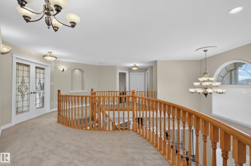 Expansive landing featuring a curved staircase with natural wood railings, decorative stained-glass French doors, and a dramatic arched window - 13527 158 Avenue Nw, Edmonton, AB - Indoor Photo Showing Other Room