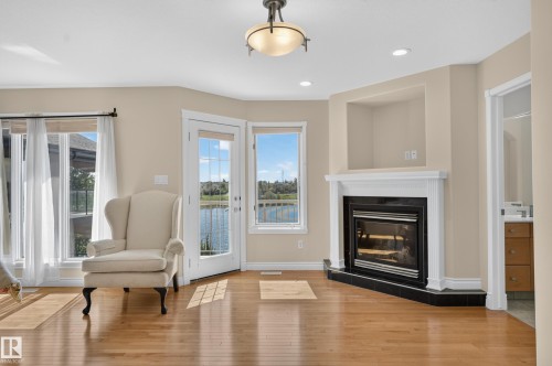Hardwood flooring, a built-in fireplace with a black tile hearth, and a mantel with an integrated niche - 13527 158 Avenue Nw, Edmonton, AB - Indoor Photo Showing Living Room With Fireplace