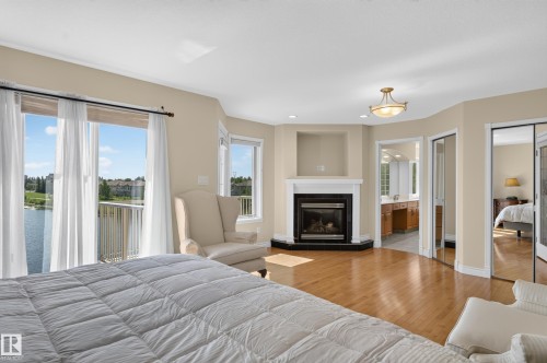 Hardwood flooring, corner fireplace with a white mantel, built-in niche, and glass sliding closet doors - 13527 158 Avenue Nw, Edmonton, AB - Indoor With Fireplace
