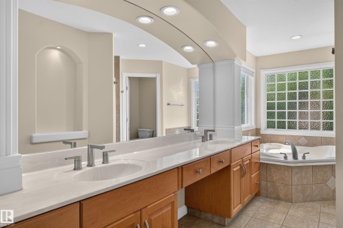 Dual vanities with undermount sinks, wood-finish cabinetry, and a light-toned countertop - 13527 158 Avenue Nw, Edmonton, AB - Indoor Photo Showing Bathroom