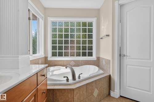 Built-in soaking tub with brushed nickel fixtures, complemented by a glass block window and a tiled surround - 13527 158 Avenue Nw, Edmonton, AB - Indoor Photo Showing Bathroom