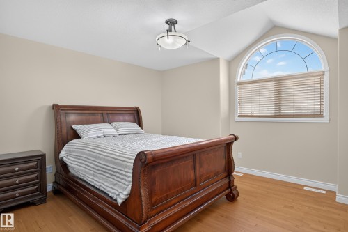 Arch-top window with blinds, wood-finish flooring, neutral wall paint, and overhead lighting - 13527 158 Avenue Nw, Edmonton, AB - Indoor Photo Showing Bedroom