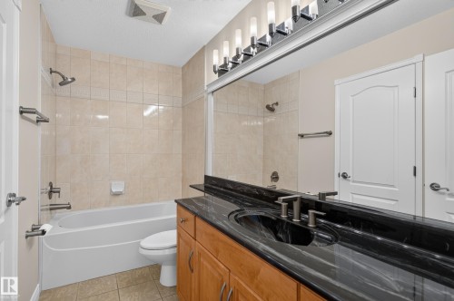 Built-in vanity with wood-finish cabinetry, black countertop, and undermount sink - 13527 158 Avenue Nw, Edmonton, AB - Indoor Photo Showing Bathroom
