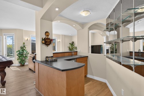 Wet bar featuring a sink, wood-finish cabinetry, and dark countertops - 13527 158 Avenue Nw, Edmonton, AB - Indoor
