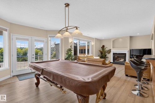 Open-concept room featuring wood-finish flooring, a fireplace with a mantel, and French doors - 13527 158 Avenue Nw, Edmonton, AB - Indoor Photo Showing Other Room With Fireplace