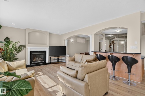 Living space featuring a corner fireplace with a white mantel, wood-finish flooring, and recessed lighting - 13527 158 Avenue Nw, Edmonton, AB - Indoor Photo Showing Living Room With Fireplace