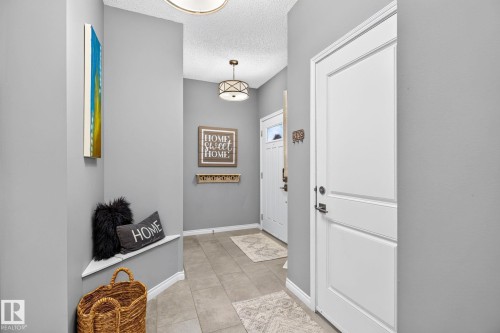 Recessed entryway with light gray walls, large format tile flooring, and a built-in corner bench - 16512 140 Street Nw, Edmonton, AB - Indoor Photo Showing Other Room