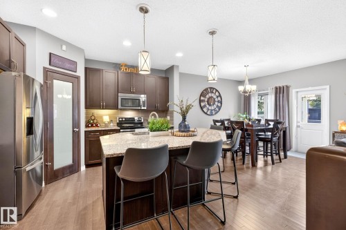 Open-concept kitchen and dining area featuring wood-finish flooring, recessed lighting, and pendant fixtures - 16512 140 Street Nw, Edmonton, AB - Indoor