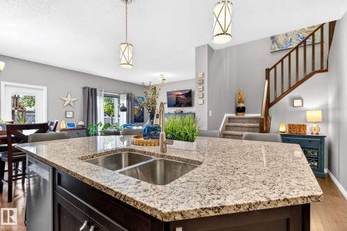 Kitchen island featuring a double basin stainless steel sink, a stainless steel dishwasher, and pendant lighting - 16512 140 Street Nw, Edmonton, AB - Indoor Photo Showing Kitchen With Double Sink