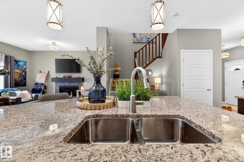 Kitchen island featuring a double basin stainless steel sink and a contemporary faucet, with granite countertops - 16512 140 Street Nw, Edmonton, AB - Indoor Photo Showing Kitchen With Double Sink With Upgraded Kitchen