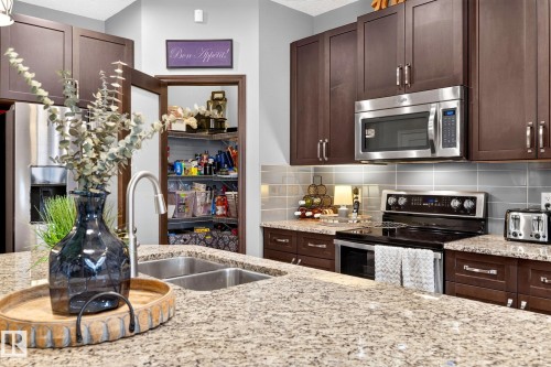 Kitchen featuring granite countertops, wood-finish cabinetry, stainless steel appliances, a double basin sink, and a walk-in pantry - 16512 140 Street Nw, Edmonton, AB - Indoor Photo Showing Kitchen With Double Sink With Upgraded Kitchen