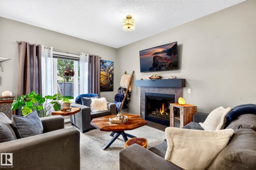 Tile-surround fireplace with a dark mantel, large window, and overhead lighting - 16512 140 Street Nw, Edmonton, AB - Indoor Photo Showing Living Room With Fireplace
