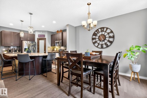 Open-concept living space with wood-finish flooring, a kitchen island featuring a light-toned countertop, and dark wood cabinetry - 16512 140 Street Nw, Edmonton, AB - Indoor Photo Showing Dining Room