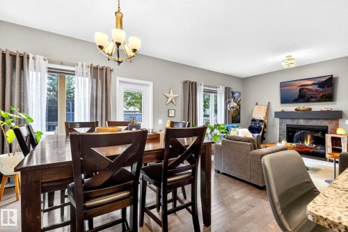 Wood-finish flooring, recessed lighting, and a fireplace with a dark mantel - 16512 140 Street Nw, Edmonton, AB - Indoor Photo Showing Dining Room With Fireplace
