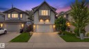 Exterior featuring a stone facade, wood-look siding, attached two-car garage, concrete driveway, and manicured landscaping - 16512 140 Street Nw, Edmonton, AB  - Outdoor With Facade 