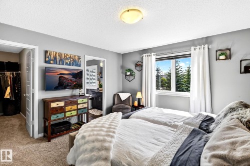 Carpeted room featuring a large window, a ceiling-mounted light fixture, and a doorway to an additional room - 16512 140 Street Nw, Edmonton, AB - Indoor Photo Showing Bedroom