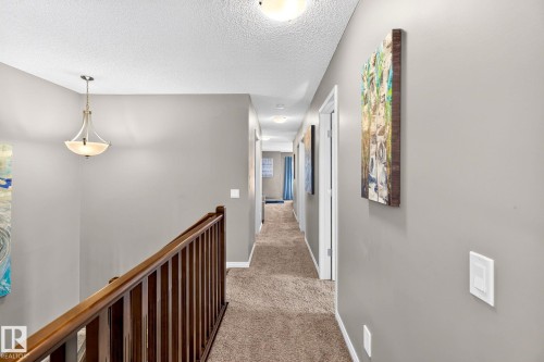 Hallway with wood-finish railing, neutral carpeting, and a semi-flush mount light fixture - 16512 140 Street Nw, Edmonton, AB - Indoor Photo Showing Other Room