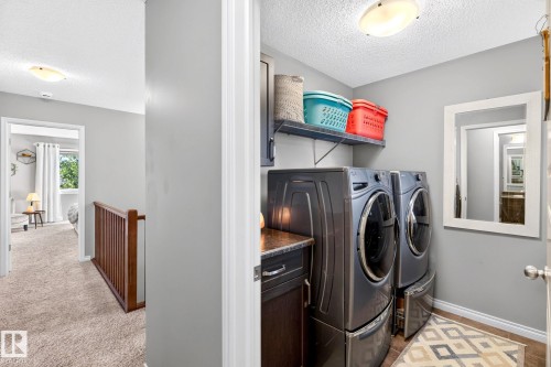 Dedicated laundry area with built-in cabinetry, countertop space, and overhead shelving - 16512 140 Street Nw, Edmonton, AB - Indoor Photo Showing Laundry Room