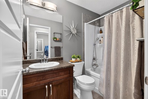 Wood-finish vanity with an oval sink, chrome faucet, and a large wall mirror - 16512 140 Street Nw, Edmonton, AB - Indoor Photo Showing Bathroom