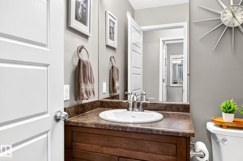 Powder room featuring a wood-finish vanity with an integrated sink, polished chrome faucet, and full-width mirror - 16512 140 Street Nw, Edmonton, AB - Indoor Photo Showing Bathroom