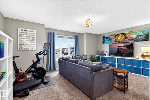 Spacious room featuring neutral painted walls, carpeted flooring, a large window, and a built-in storage unit - 16512 140 Street Nw, Edmonton, AB - Indoor