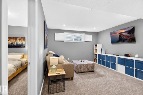 Recessed lighting, wall-mounted television, built-in shelving, gray wall color, and light-toned carpet flooring - 16512 140 Street Nw, Edmonton, AB - Indoor