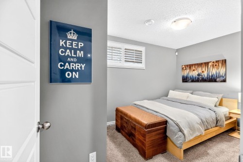 Wood-frame bed with neutral carpeting, window with louvered shutters, and ceiling-mounted light fixture - 16512 140 Street Nw, Edmonton, AB - Indoor Photo Showing Bedroom