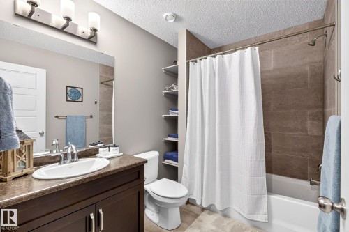 Vanity with an integrated sink, dark wood-finish cabinetry, and a textured countertop - 16512 140 Street Nw, Edmonton, AB - Indoor Photo Showing Bathroom