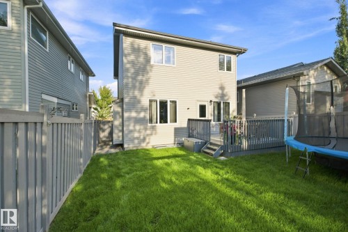 Expansive green lawn with a gray wood-plank deck, and light-colored siding - 16512 140 Street Nw, Edmonton, AB - Outdoor With Deck Patio Veranda With Exterior