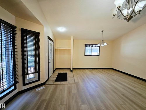 Wood-finish flooring throughout, bay window with dark blinds, tiled entry, and a built-in shelf - 11625 88 Street Nw, Edmonton, AB 