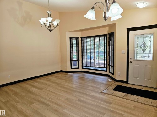 Wood-finish flooring, bay window with blinds, decorative front entry door, and two chandelier light fixtures - 11625 88 Street Nw, Edmonton, AB 