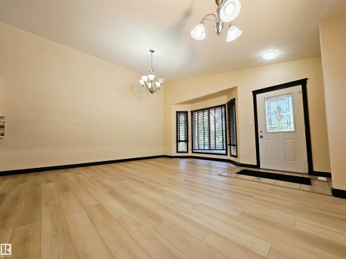 Wood-finish flooring, bay windows with blinds, recessed lighting, decorative chandelier, and a front entry door with leaded glass insert - 11625 88 Street Nw, Edmonton, AB 