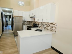 Kitchen featuring white cabinetry, light-colored countertops, stainless steel appliances, and a mosaic tile backsplash - 