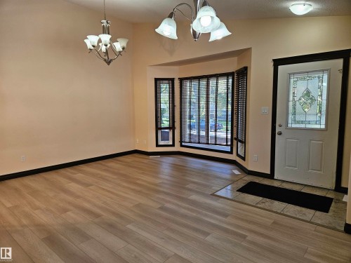 Light wood-finish flooring with tile entry, decorative glass front door, bay window, and two ceiling-mounted light fixtures - 11625 88 Street Nw, Edmonton, AB 