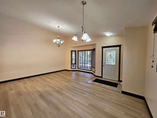 Light wood-finish flooring throughout, bay window with dark trim, decorative front entry door, and recessed lighting - 11625 88 Street Nw, Edmonton, AB 