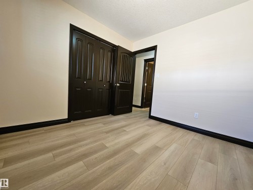 Light-toned wood-finish flooring with dark trim and doors - 11625 88 Street Nw, Edmonton, AB 