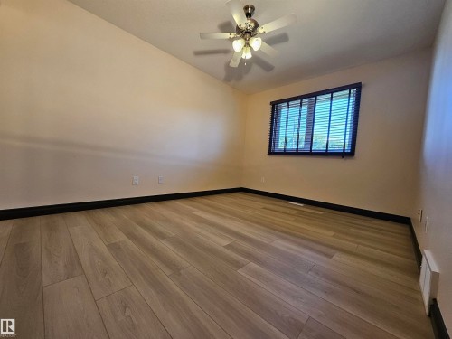 Wood-finish flooring with dark baseboards, a ceiling fan with integrated lighting, and a window with blinds - 11625 88 Street Nw, Edmonton, AB 