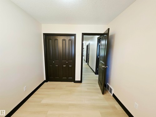 Neutral wall finishes, light wood-finish flooring, dark paneled doors, and ceiling texture - 11625 88 Street Nw, Edmonton, AB 