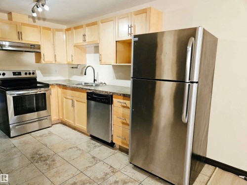 Kitchen featuring wood-finish cabinetry, stainless steel appliances, speckled countertops, a double basin sink with a gooseneck faucet, and tile flooring - 11625 88 Street Nw, Edmonton, AB 