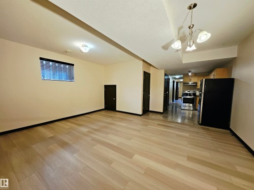 Light wood-finish flooring, recessed lighting, window with blinds, and a kitchen with stainless steel appliances - 11625 88 Street Nw, Edmonton, AB 
