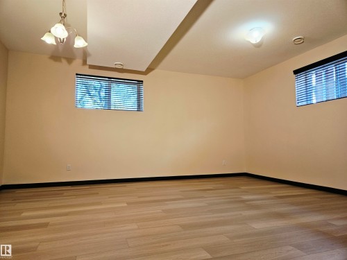 Light wood-finish flooring, two windows with blinds, recessed ceiling lighting, and a multi-bulb ceiling fixture - 11625 88 Street Nw, Edmonton, AB 