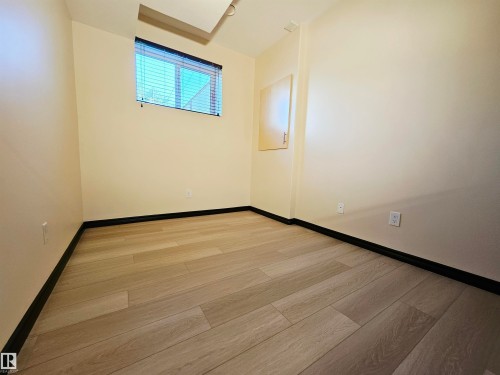 Wood-finish flooring with black trim, light-toned walls, and a window with blinds - 11625 88 Street Nw, Edmonton, AB 
