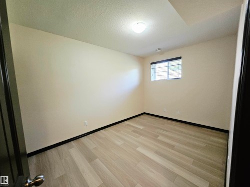 Wood-finish flooring, single window with blinds, ceiling-mounted light fixture, and neutral wall tones - 11625 88 Street Nw, Edmonton, AB 