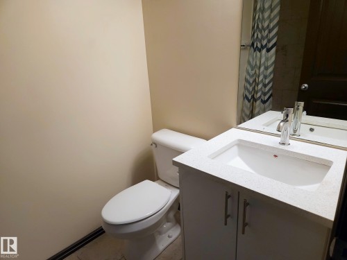 White vanity with a light-toned countertop, undermount sink, and chrome faucet - 11625 88 Street Nw, Edmonton, AB 